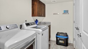 A laundry room with a washing machine, dryer, wooden cabinet, and a trash bin. - 4-C Canyonlands Redcliff Condo (Pool View) (Moab)