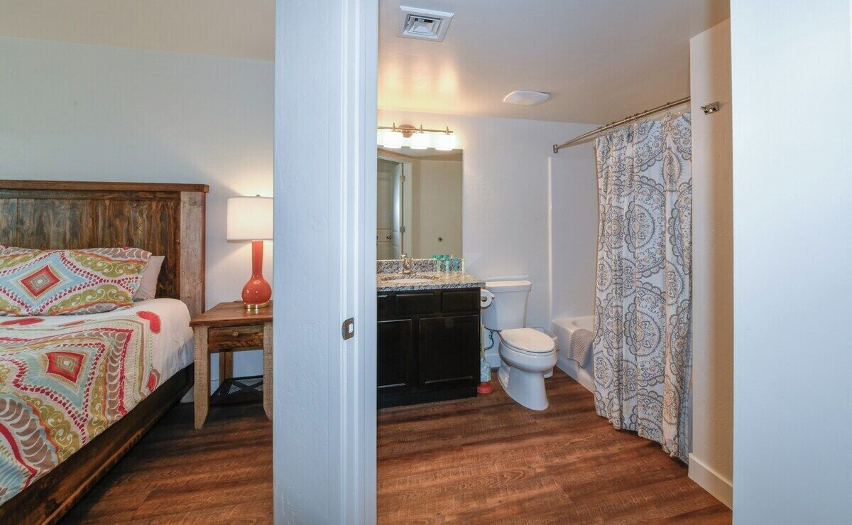 A bedroom with a wooden headboard, a bedside table with a lamp, and a patterned bedspread.