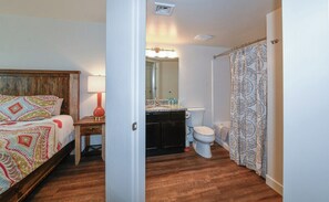 A bedroom with a wooden headboard, a bedside table with a lamp, and a patterned bedspread. - 2-C Spanish Valley Condo (Moab)