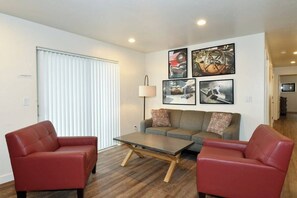 A living room with a sofa, two armchairs, a coffee table, and wall art. - 2-C Spanish Valley Condo (Moab)