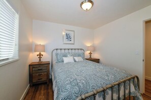 A bedroom with a bed, two bedside tables, a nightstand, a wall-mounted picture, and a ceiling light fixture. - 2-C Spanish Valley Condo (Moab)