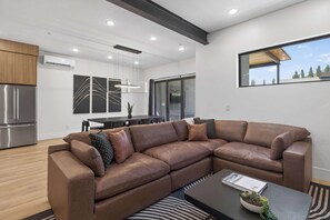 A modern living room with a sectional sofa, a dining area, and a kitchen with stainless steel appliances. - Brand New Moab Luxury at Copper View (Moab)