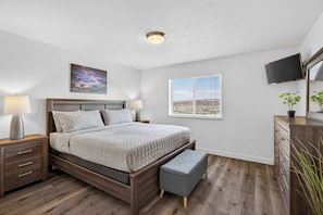A bedroom with a bed, bedside tables, a nightstand, a window, and a television. - 4-L Stargazing Redcliff Condo (Top Floor) (Moab)