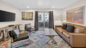 A modern hotel room with a sofa, armchair, coffee table, and a flat-screen TV. - 2-F Castle Valley Redcliff Condo (Moab)