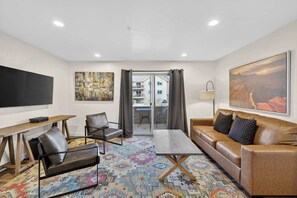 A modern hotel room with a sofa, armchair, coffee table, and a flat-screen TV. - 2-F Castle Valley Redcliff Condo (Moab)