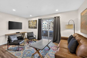 A living room with a sofa, two chairs, a coffee table, a TV, and a painting on the wall. - 2-F Castle Valley Redcliff Condo (Moab)