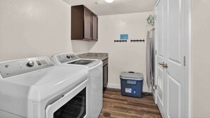 A laundry area with two washing machines, a dryer, a blue storage bin, and a door with a towel rack. - 2-F Castle Valley Redcliff Condo (Moab)