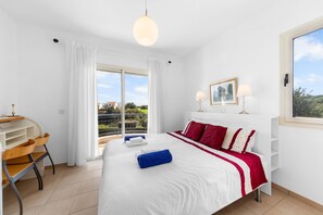 A hotel room with a bed, a desk, a chair, a window, and a balcony. - Villa Latchi Marina 3 -  a villa that sleeps 6 guests  in 3 bedrooms (Latchi)