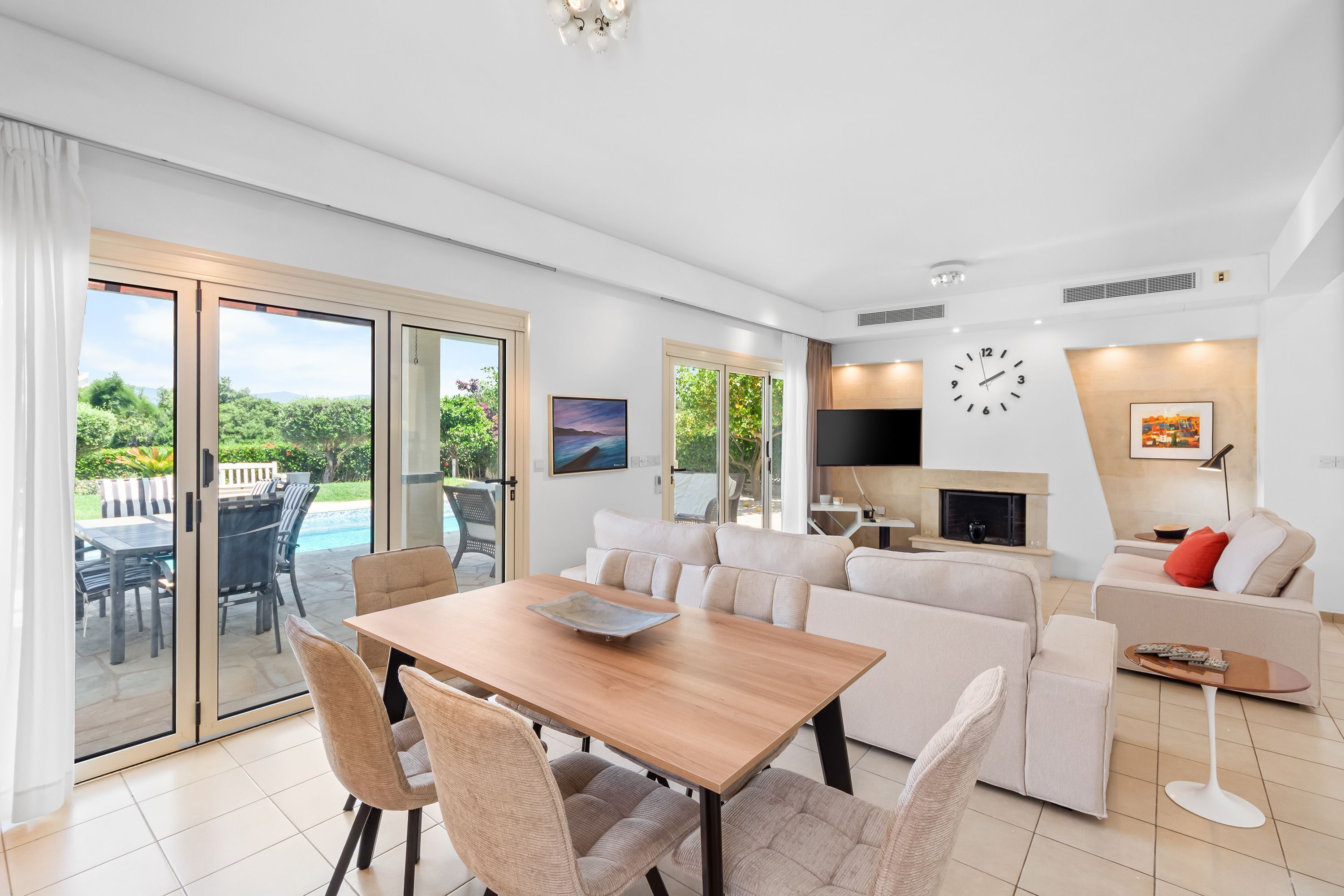 A modern living room with a wooden dining table, sofas, and a TV.