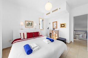 Ein Hotelzimmer mit einem großen Bett, einem Nachttisch, einem Kleiderschrank, einem Schreibtisch und einem Balkon.
