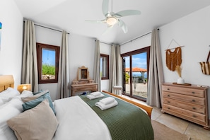 Ein Hotelzimmer mit Bett, Schminktisch, Kommode und Blick auf den Strand.