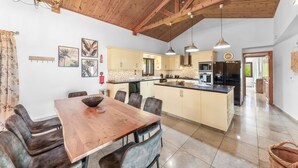 Una cocina amplia con vigas de madera, un comedor con mesa y sillas de madera, y una isla central.