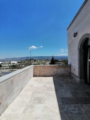 Una terraza en la azotea con vistas despejadas del paisaje circundante, una lámpara y la entrada de un edificio.