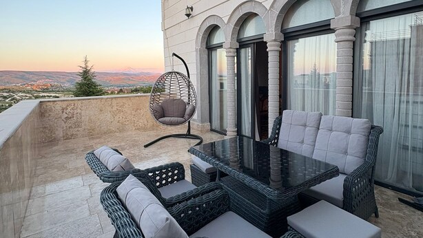 Una terrazza con mobili in vimini, un tavolo in vetro e una sedia a dondolo.