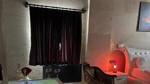 Una stanza con una vasca da bagno grande, una sedia, un tavolino e un letto.