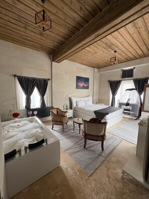 Un dormitorio amplio con una cama grande, una zona de estar con sillas, una bañera y un cuadro en la pared.