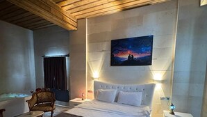 Una camera da letto con un letto grande, un comodino con una lampada, una sedia, un tavolino e un quadro raffigurante una scena notturna appeso al muro.
