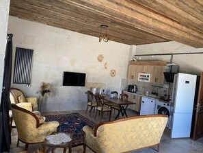 A living room with a TV, dining area, and kitchen with appliances.