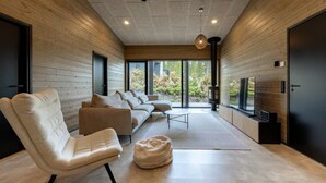 Un salon moderne comprenant un canapé, un fauteuil, une petite table et un téléviseur.