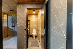 Um banheiro moderno com piso de mármore, box de chuveiro em madeira e vaso sanitário.