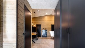 Un couloir mène à une salle à manger avec un mur en bois, un plancher foncé et un plafond moderne.