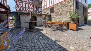 Ein Innenhof mit Steinplatten, Holztischen und -stühlen sowie traditionellen Fachwerkhäusern.