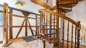 Eine Wendeltreppe aus Holz mit Geländer, Holzboden und einer Tür mit Fenster im Hintergrund.