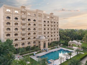 Un grand hôtel doté de nombreux balcons, d’une piscine et d  ’une végétation luxuriante.