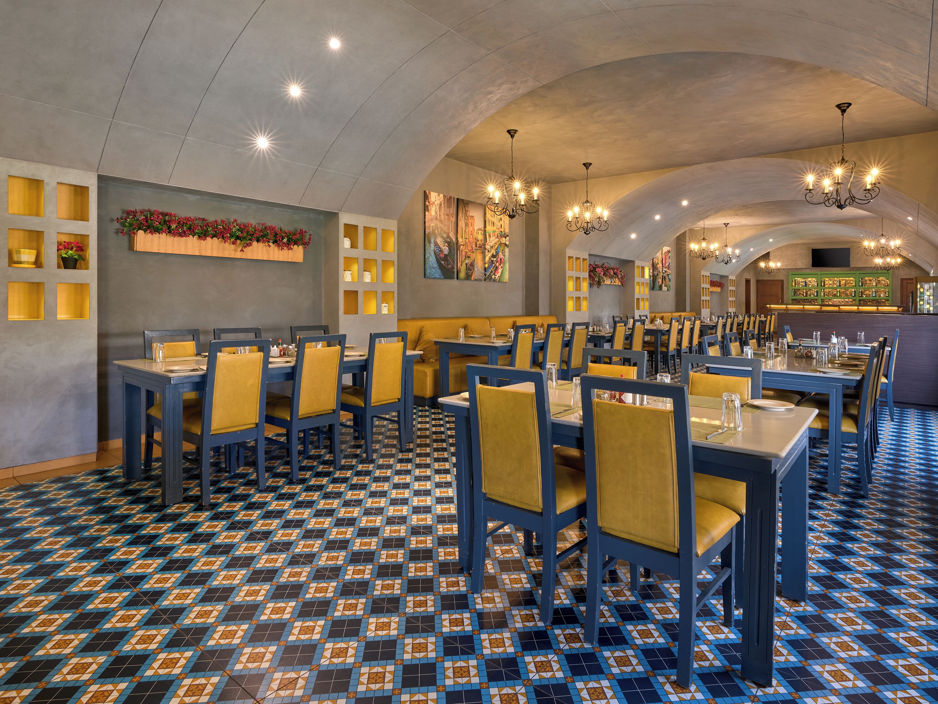 A restaurant with blue and yellow chairs, tables, and a patterned floor.