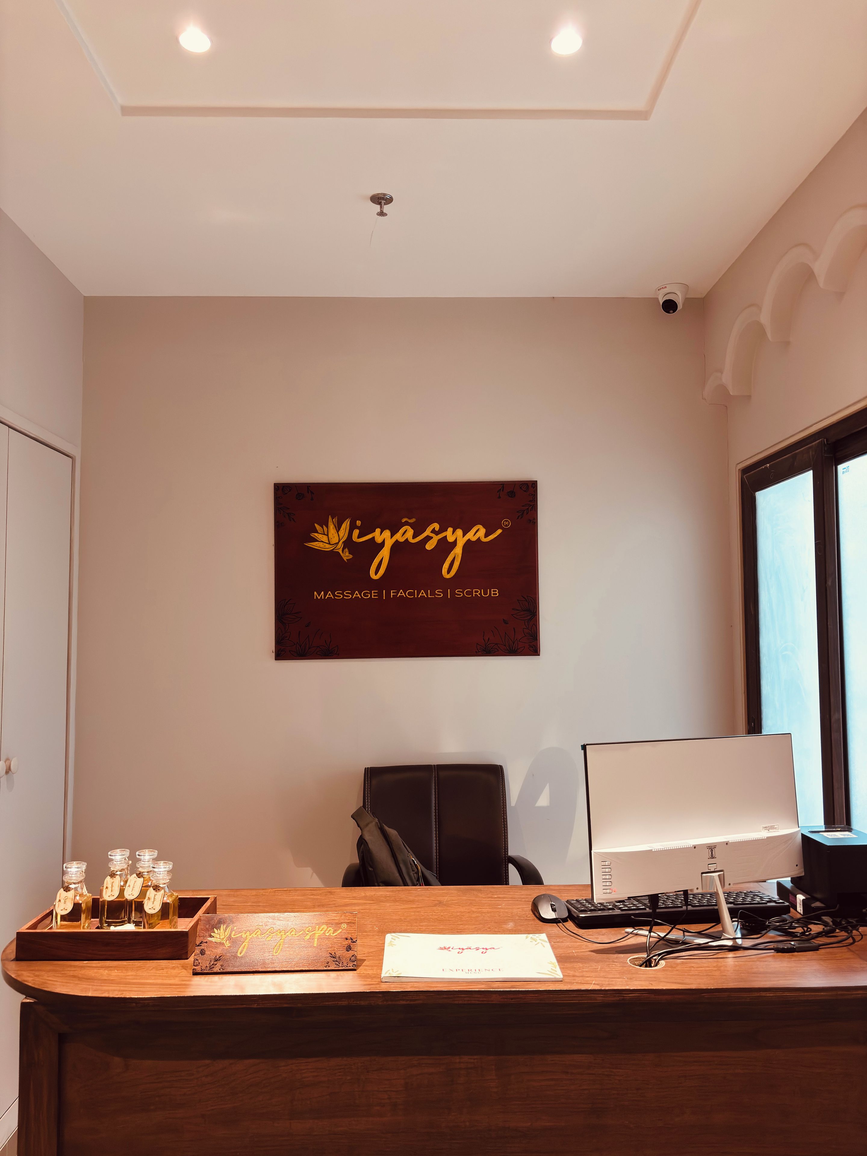 Una mesa de recepción con una computadora, una silla y un cartel en la pared.