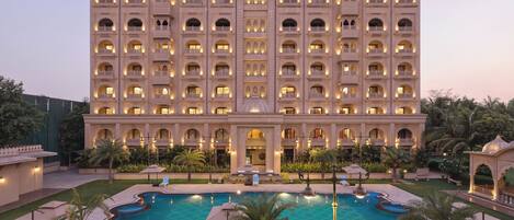 Un hotel grande con varios balcones, una piscina y abundante vegetación.
