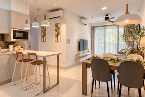 Una cocina moderna con comedor, armarios blancos e iluminación colgante.