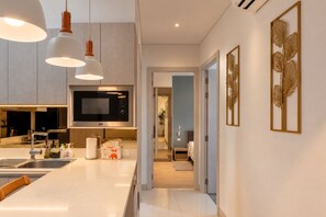 A modern kitchen with a built-in microwave, a sink, and pendant lighting. - Modern 2-Bedroom Apartment at Cassia Phuket (Choeng Thale)