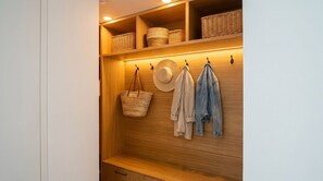 Ein Holzregal mit Körben, einem Hut und einer Jacke.