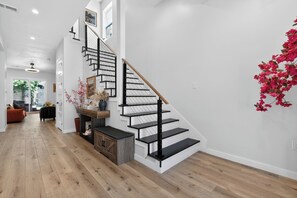 Eine Treppe mit schwarzen Geländern und Holzbeschlägen, ein Holzschrank und eine an der Wand befestigte Pflanze.