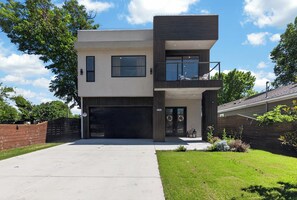 Ein modernes, zweistöckiges Haus mit Garage, großen Fenstern und einem Balkon.