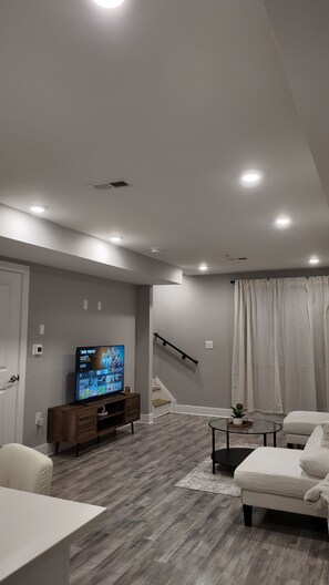 Ein modernes Wohnzimmer mit Flachbildfernseher, einer Treppe und einem Essbereich.