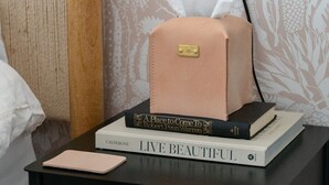 Et natbord med en tissueske, en bog med titlen 'LIVE BEAUTIFUL' og en notesbog.