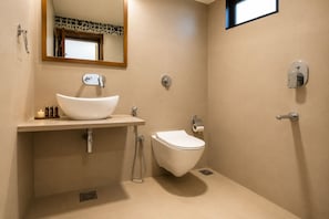 A bathroom with a white sink, toilet, and shower. - Bungalow Seven (Mount Abu)