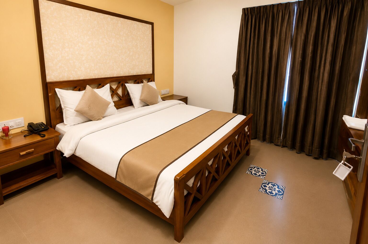 Une chambre d’hôtel comprenant un lit, une table de chevet avec un téléphone, une commode, un rideau et un luminaire fixé au mur.