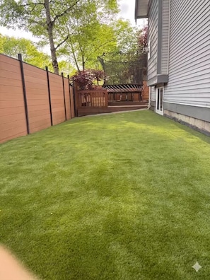 A well-maintained backyard with a wooden fence, a pergola, and a house with siding. - Amazing 2BR Basement Suite (Langley Township)
