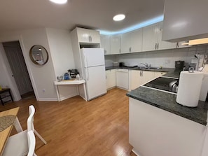 A compact kitchen with white cabinets, a built-in oven, and a granite countertop. - Amazing 2BR Basement Suite (Langley Township)