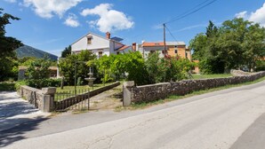 Ein Wohngebiet mit Häusern, einer Steinmauer, einer gepflasterten Straße und blauem Himmel.