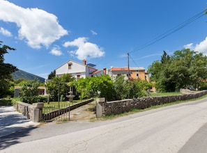 A residential area with houses, a stone wall, a paved road, and a clear blue sky. - Villa Danci (Mali Losinj)