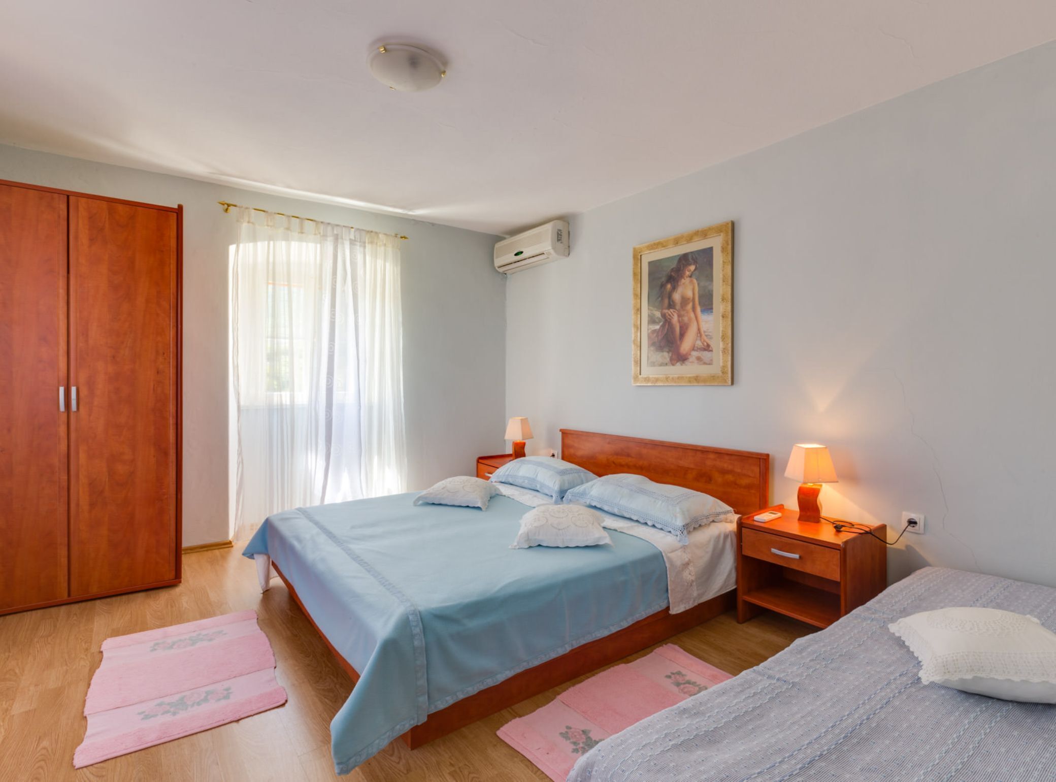 A bedroom with a bed, bedside tables, a wardrobe, and a painting on the wall.