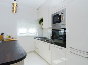 A modern kitchen with white cabinets, a black countertop, a built-in microwave, and an oven.