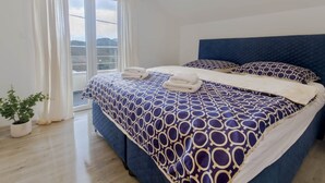 Una camera da letto con un letto grande, vista sull'esterno e una pianta in vaso.