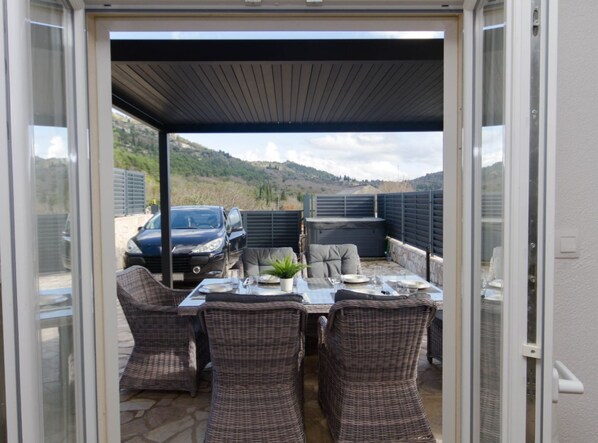 An outdoor patio with wicker furniture, a table set for dining, and a car parked outside.