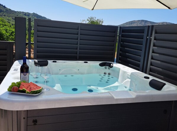 A hot tub with a table set for two, a bottle of wine, and watermelon slices.