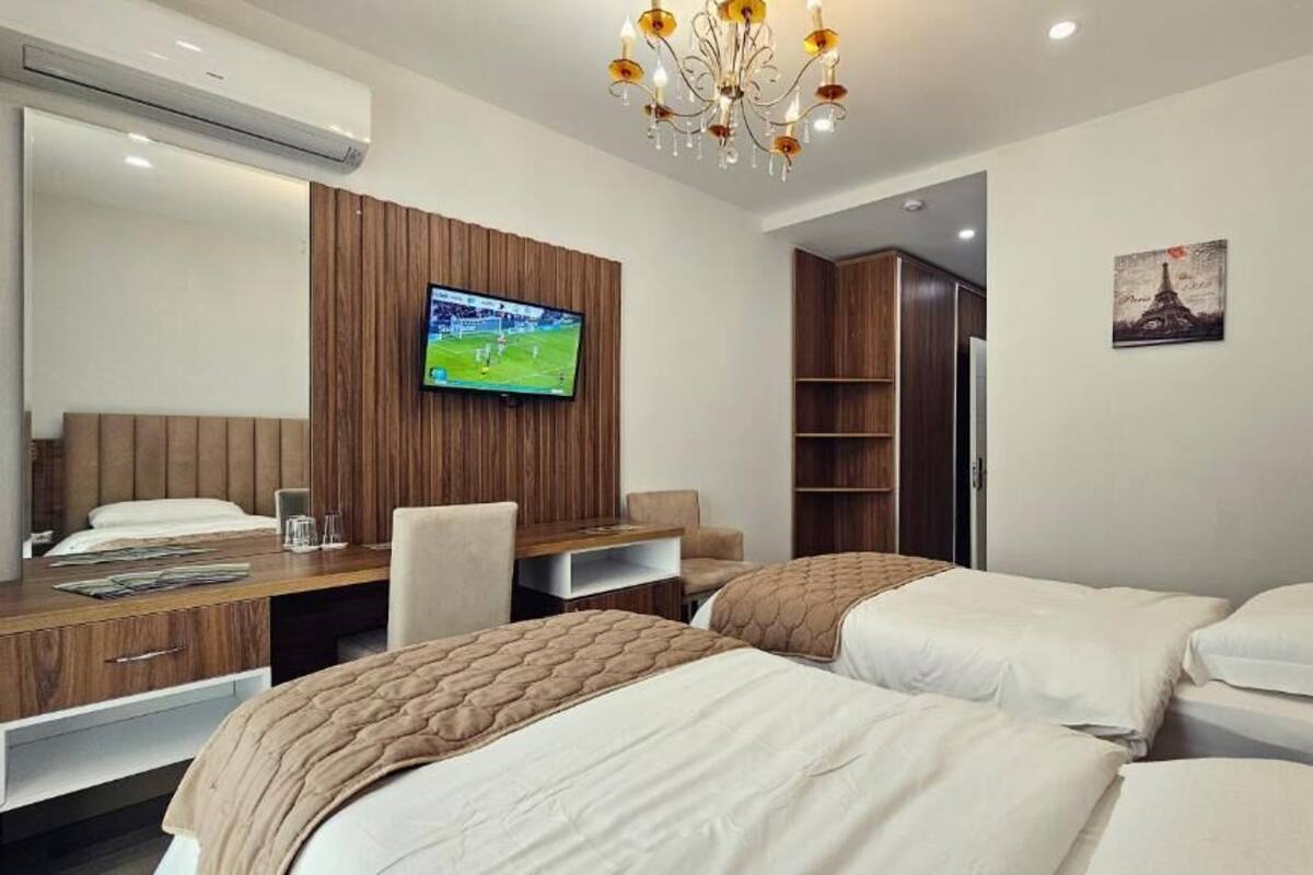 Una habitación de hotel con dos camas, un escritorio con televisor, un armario y una araña.
